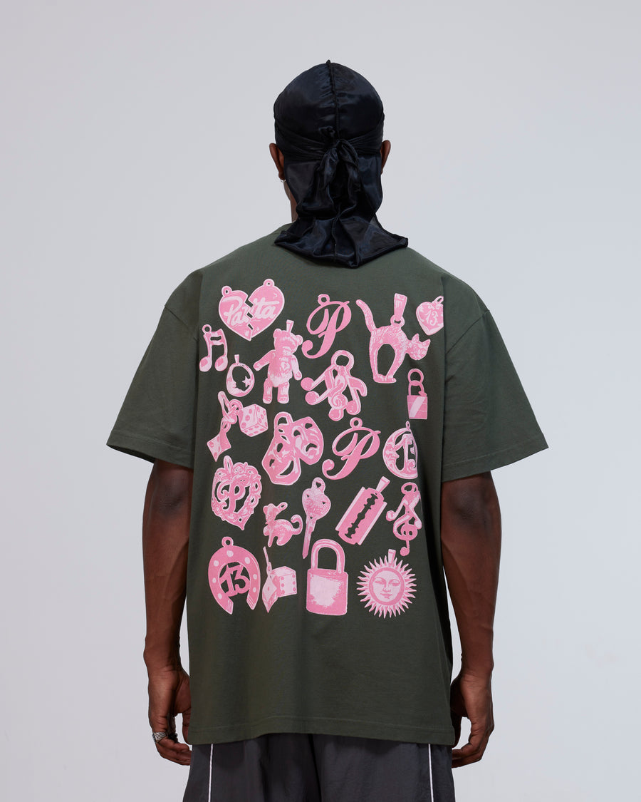 Back view of a model wearing the Patta Charm T-Shirt in climbing ivy green with pink charms artwork.