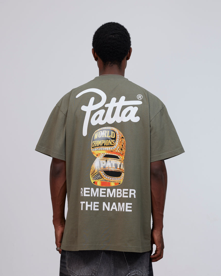 Back view of model wearing the Patta Championship T-Shirt in dusty olive with graphic print.