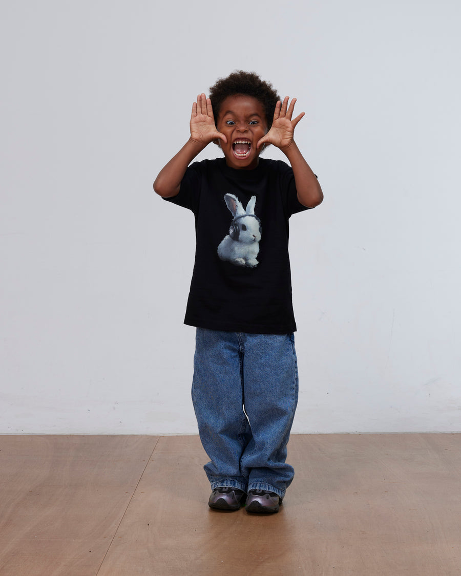 Boy wearing the black Patta Kids Bunny T-Shirt featuring a bunny graphic print and blue jeans.